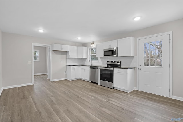 kitchen with stainless steel appliances, light wood-type flooring, white cabinets, and sink