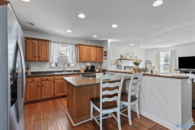 kitchen with a sink, wood-type flooring, a healthy amount of sunlight, and stainless steel refrigerator with ice dispenser