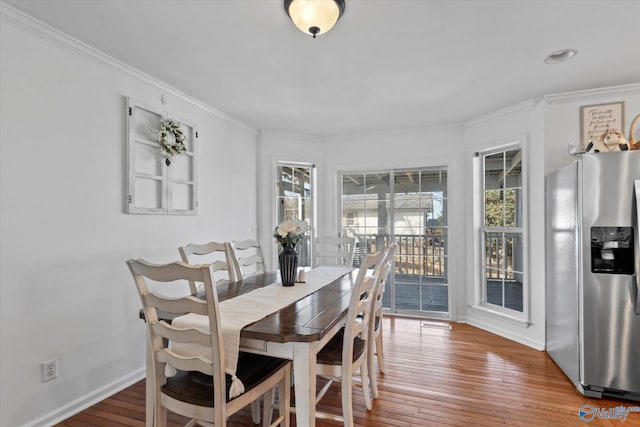 dining room featuring baseboards, hardwood / wood-style floors, and ornamental molding