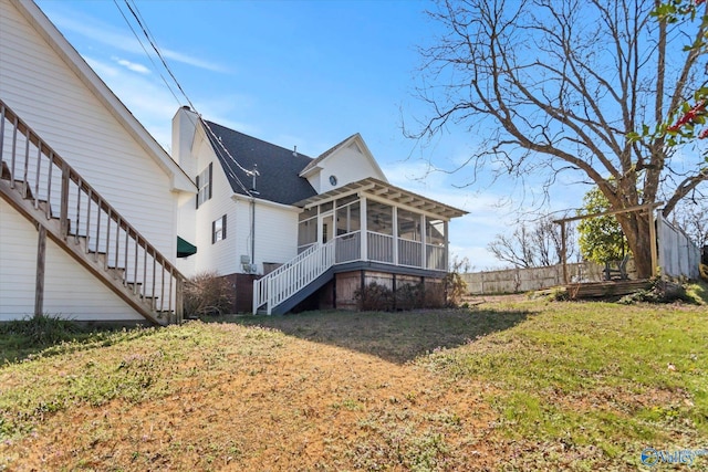 back of house with stairway, fence, a yard, a sunroom, and a chimney