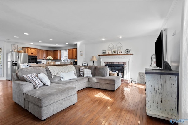living area with recessed lighting, a brick fireplace, and hardwood / wood-style flooring