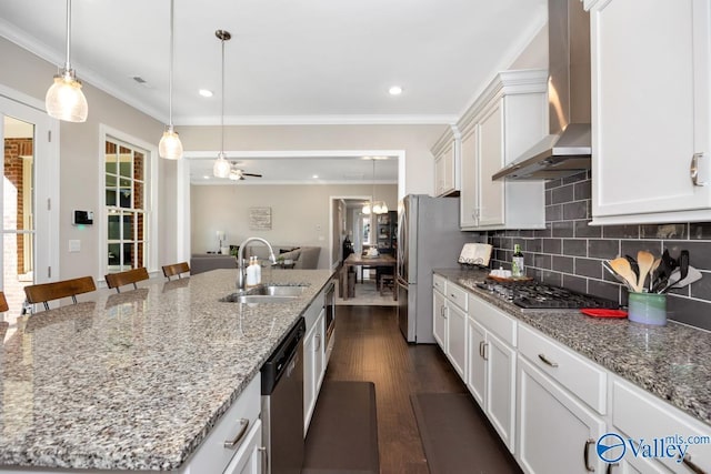 kitchen with an island with sink, appliances with stainless steel finishes, a breakfast bar, wall chimney range hood, and a sink