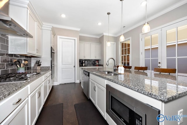 kitchen with stainless steel appliances, a kitchen island with sink, wall chimney exhaust hood, and white cabinetry