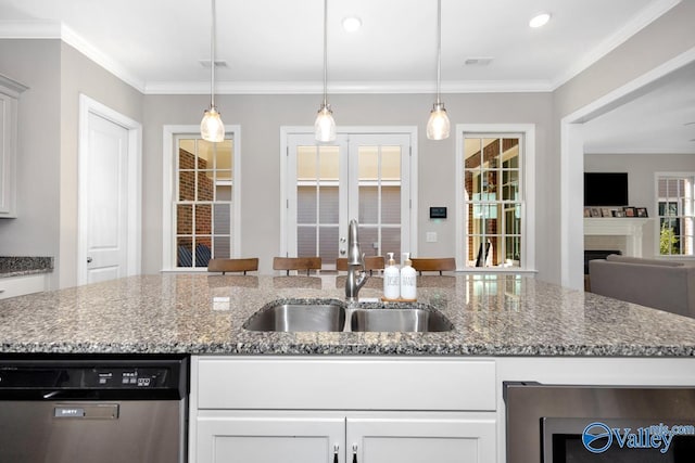 kitchen with a sink, light stone counters, stainless steel dishwasher, and decorative light fixtures