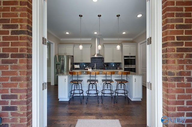 kitchen featuring an island with sink, stone countertops, a breakfast bar area, and decorative light fixtures