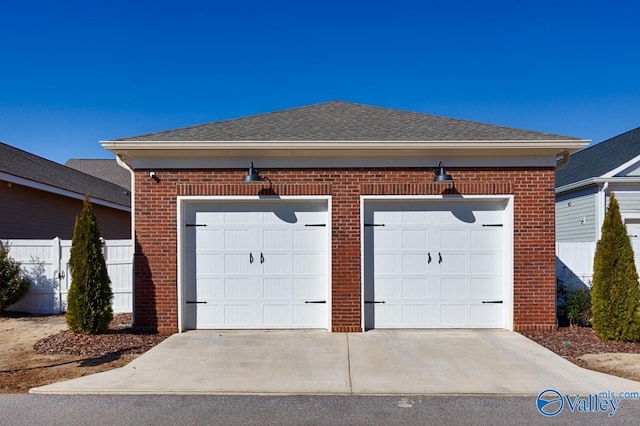 garage featuring driveway and fence