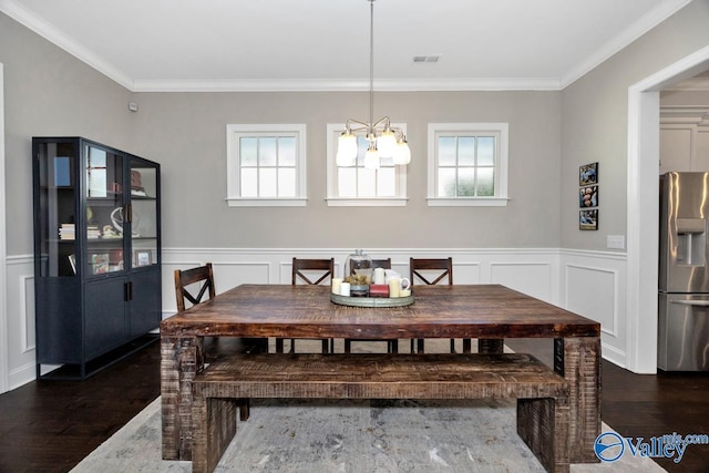 dining room with a wainscoted wall, crown molding, dark wood-style flooring, visible vents, and an inviting chandelier