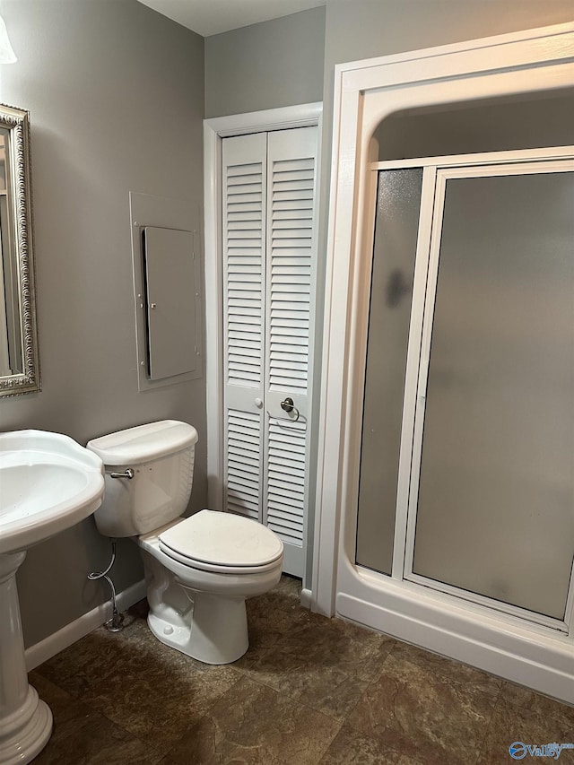 bathroom featuring toilet, a stall shower, a closet, and baseboards