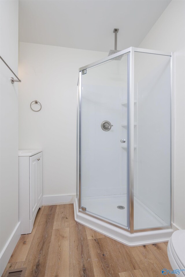 bathroom with toilet, hardwood / wood-style flooring, and a shower with shower door