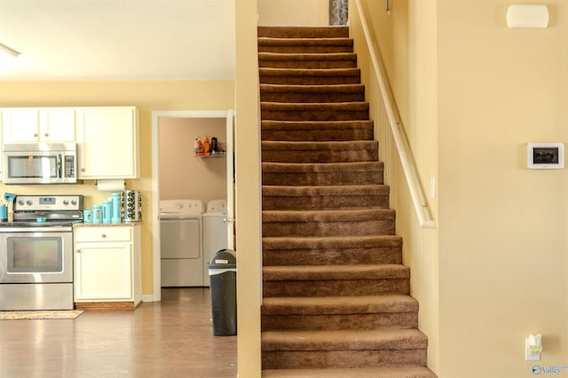 stairway with hardwood / wood-style flooring and washer and dryer