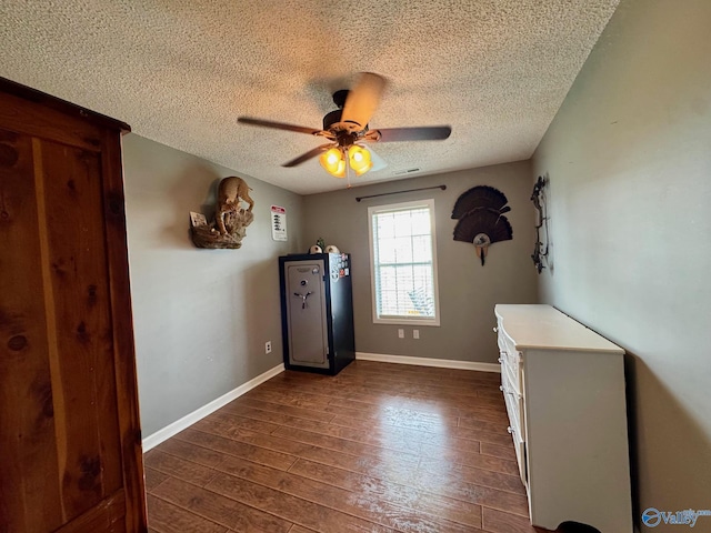 28035 Holland Gin Rd, Elkmont, AL 35620 - unfurnished bedroom featuring a textured ceiling, dark wood-type flooring, and a ceiling fan