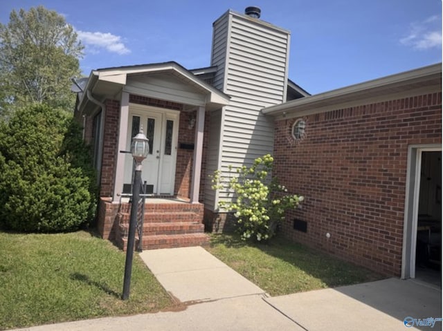 view of front facade featuring a chimney, a front lawn, crawl space, and brick siding