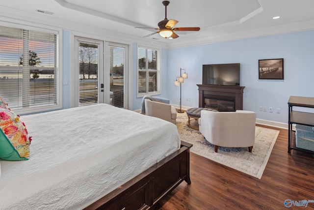 bedroom with dark hardwood / wood-style flooring, access to exterior, ceiling fan, a raised ceiling, and crown molding