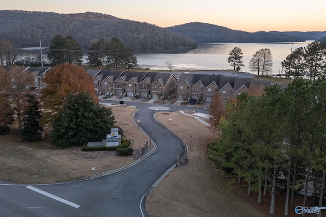 aerial view at dusk featuring a water and mountain view