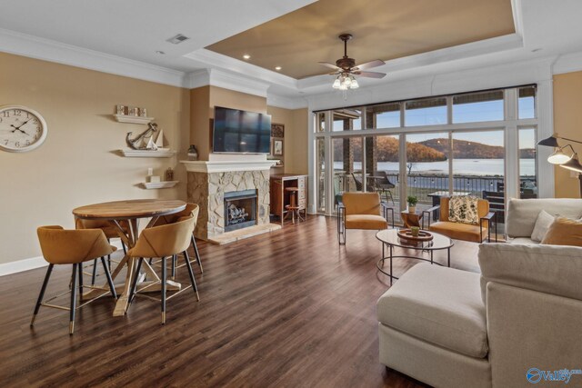 living room with dark hardwood / wood-style flooring, a tray ceiling, a fireplace, and ornamental molding