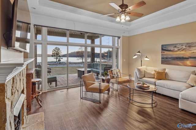 living room with crown molding, hardwood / wood-style flooring, a raised ceiling, and ceiling fan