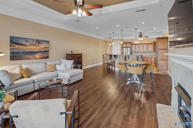 living room featuring ornamental molding, a fireplace, dark hardwood / wood-style flooring, and a tray ceiling