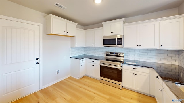 kitchen with stainless steel appliances, white cabinets, and light hardwood / wood-style flooring