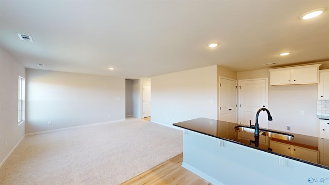 kitchen featuring sink, light carpet, and white cabinets