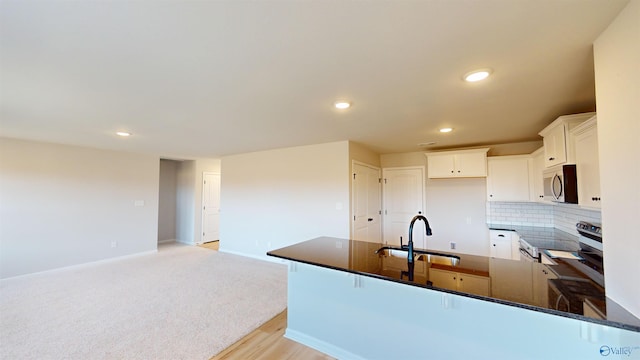 kitchen featuring white cabinetry, sink, dark stone countertops, backsplash, and stainless steel appliances