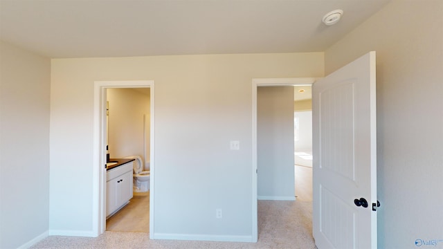 unfurnished bedroom featuring connected bathroom and light carpet