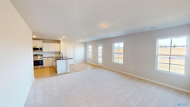 kitchen with sink, white cabinetry, stainless steel appliances, tasteful backsplash, and light colored carpet