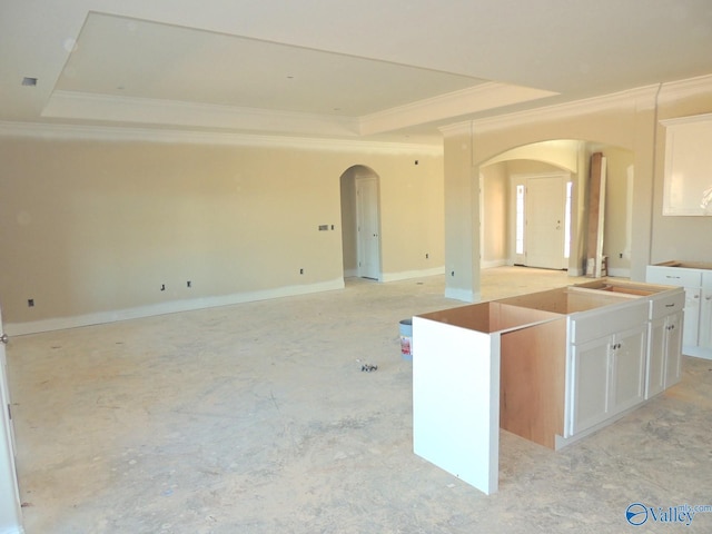 kitchen featuring sink, a center island, ornamental molding, a tray ceiling, and white cabinets