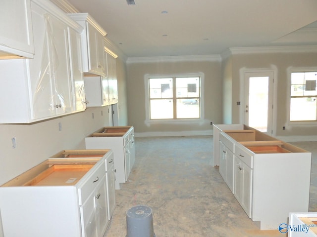 kitchen with crown molding, a kitchen island, a wealth of natural light, and white cabinets