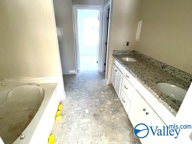 bathroom with a tub to relax in, vanity, and concrete floors