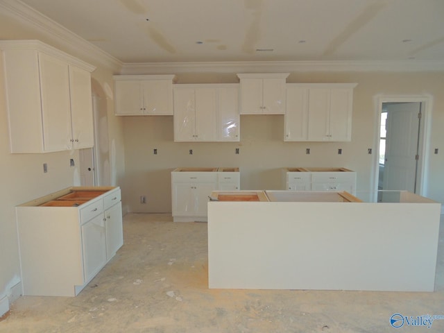 kitchen with white cabinetry, a kitchen island, and ornamental molding