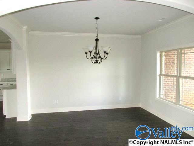 unfurnished dining area with crown molding, dark wood-type flooring, and an inviting chandelier