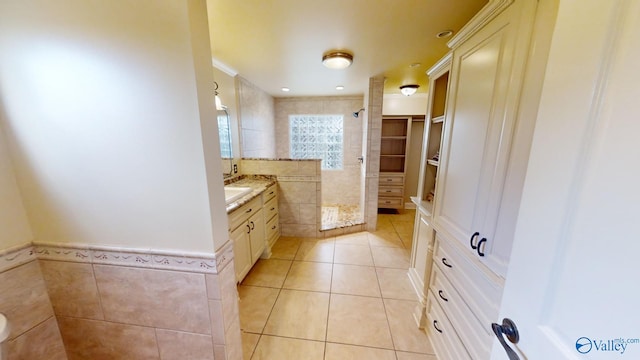 bathroom featuring walk in shower, vanity, tile walls, and tile patterned flooring