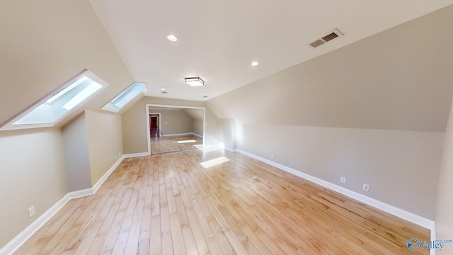 bonus room with light hardwood / wood-style flooring and vaulted ceiling with skylight