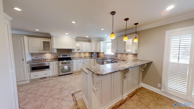 kitchen with a kitchen breakfast bar, kitchen peninsula, appliances with stainless steel finishes, and tasteful backsplash