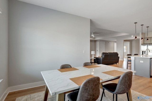 dining space featuring light wood-style floors and baseboards