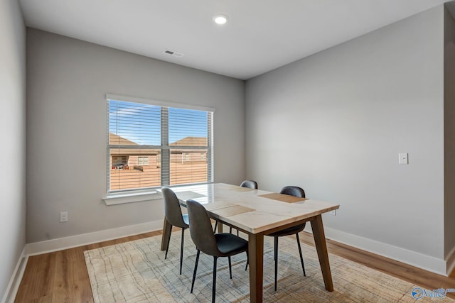 dining space with wood finished floors, visible vents, and baseboards