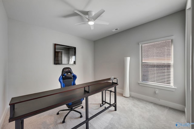 office featuring a ceiling fan, visible vents, light carpet, and baseboards