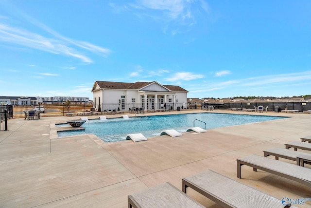 community pool with a patio area and fence