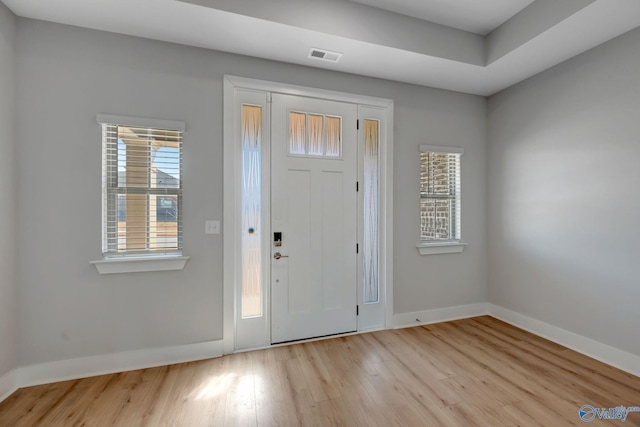 foyer entrance featuring light wood-style flooring, visible vents, and baseboards