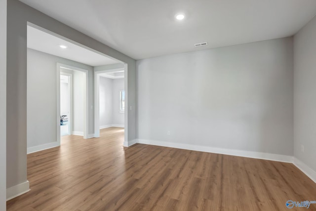 spare room featuring recessed lighting, wood finished floors, visible vents, and baseboards