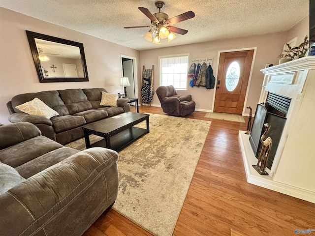 living room featuring ceiling fan, hardwood / wood-style floors, and a textured ceiling