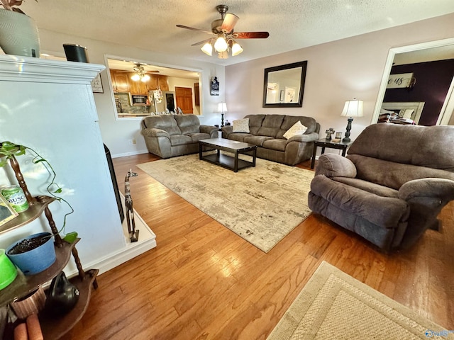 living room featuring hardwood / wood-style flooring, ceiling fan, and a textured ceiling