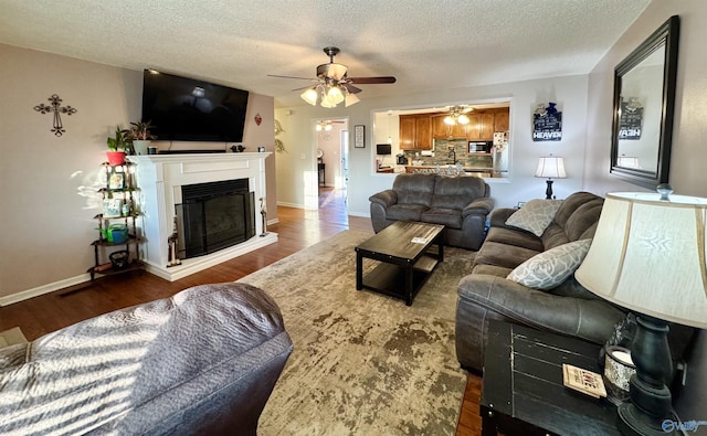 living room with ceiling fan, a textured ceiling, and dark hardwood / wood-style flooring