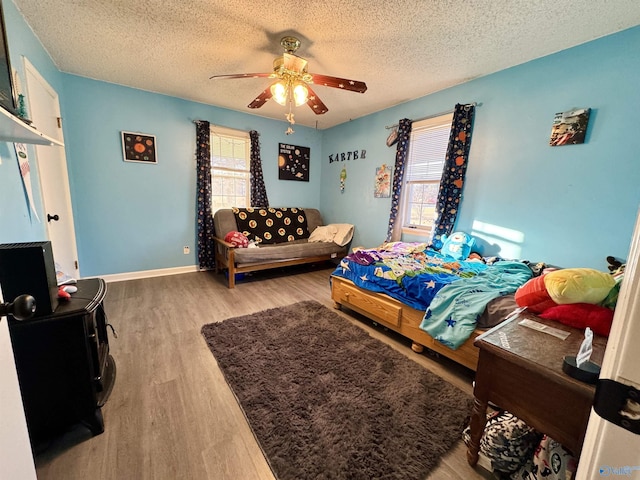 bedroom with ceiling fan, wood-type flooring, and a textured ceiling