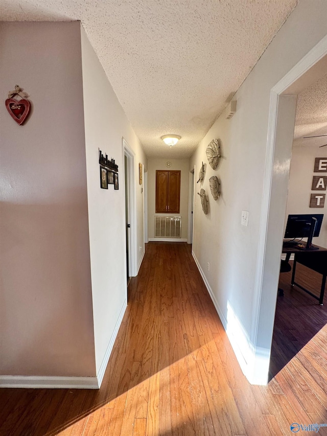 corridor featuring light hardwood / wood-style flooring and a textured ceiling