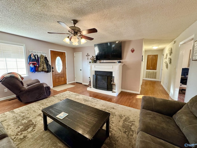 living room featuring ceiling fan, hardwood / wood-style floors, and a textured ceiling