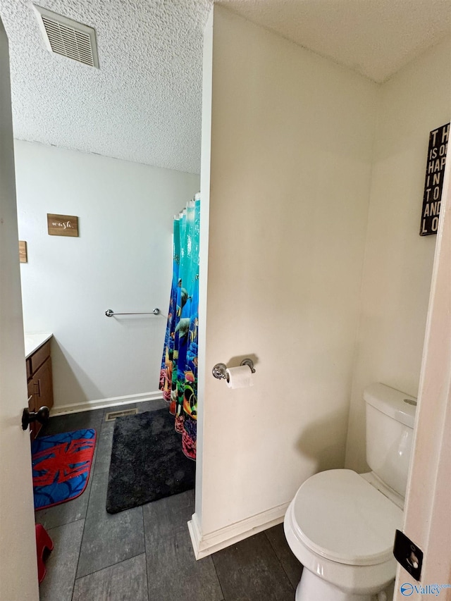 bathroom with vanity, a textured ceiling, and toilet