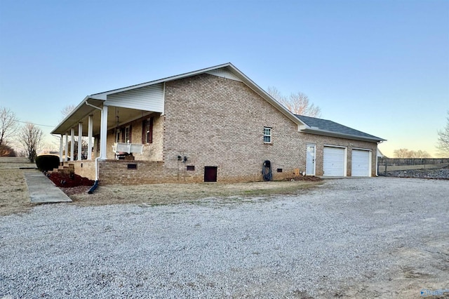 property exterior at dusk with a garage and a porch