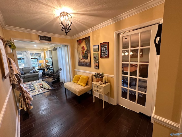 sitting room with dark wood-type flooring, a notable chandelier, a textured ceiling, and ornamental molding