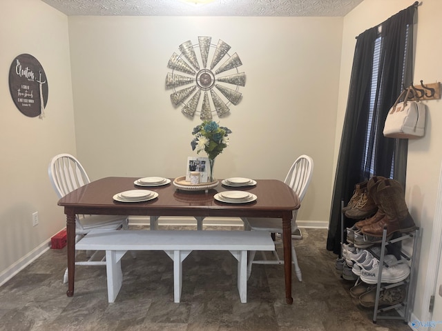 dining space with a textured ceiling and baseboards